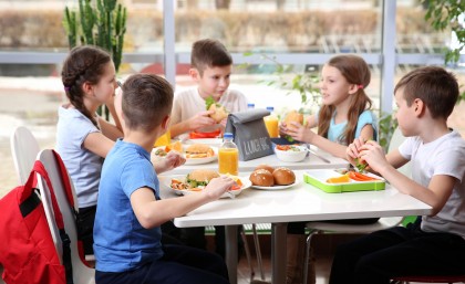 Children sitting at cafeteria table while eating lunch